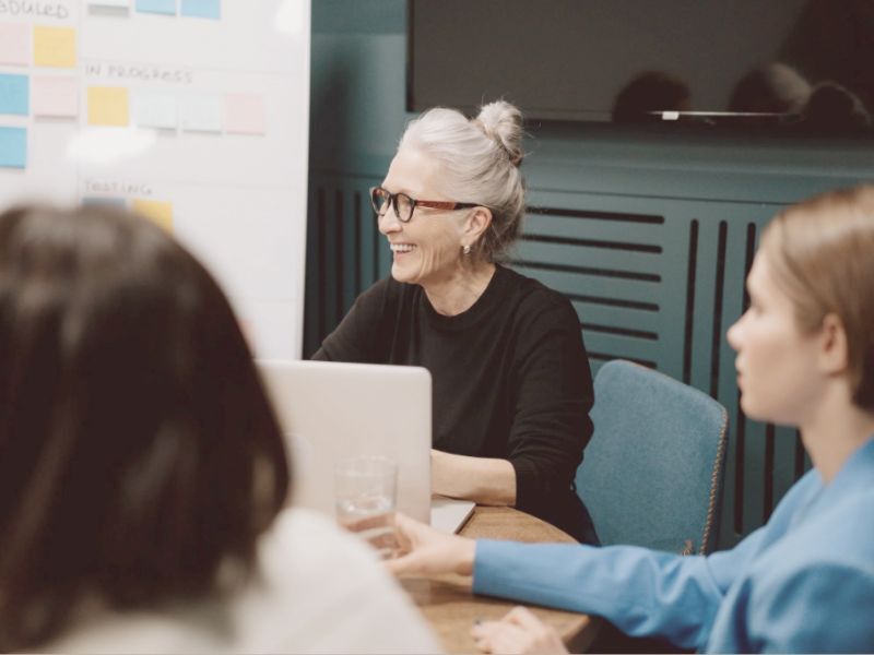 woman smiling and talking with staff around a table
