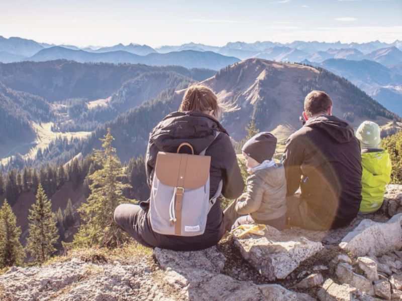 family sitting on a large rock overlooking a mountain landscape