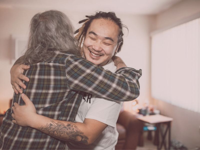 man smiling while hugging a retiree